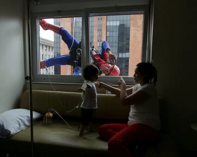 Men dressed as Spiderman jokes with patient Lucas, and his mother, looking on inside Hospital Infantil Sabara in Sao Paulo, Brazil, October 10, 2016. The costumed men cleaned the glass facade of the children's hospital and met with patients as part of the Brazil Children's Day celebrations which is held on October 12. (Photo by Paulo Whitaker/Reuters)