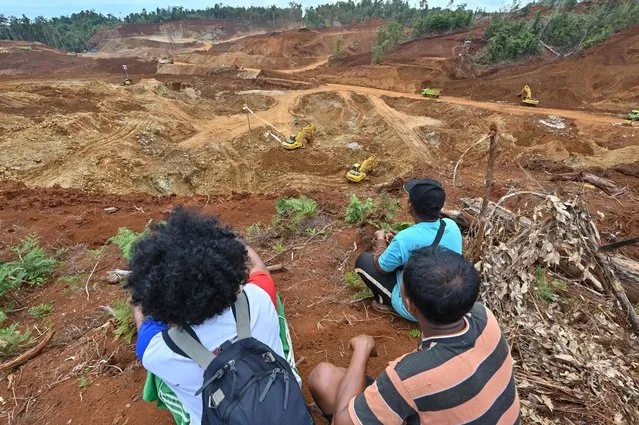 This picture taken on February 8, 2023 shows coconut farmer Hastoma (front R) and other farmers, whose lands were illegally taken by Gema Kreasi Perdana (GKP), looking at a nickel mining site operated by the company on Wawonii island, southeast Sulawesi. The dig site is part of a huge rush to Indonesia, the world's largest nickel producer, by domestic and foreign enterprises to mine the critical component used in electric vehicle batteries. (Photo by Adek Berry/AFP Photo)