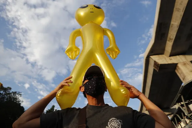 A protester holds a balloon shaped like an alien - to mock accusations that foreigners fund and direct their movement – during a rally Friday, November 27, 2020 in Bangkok, Thailand. Pro-democracy demonstrators are continuing their protests calling for the government to step down and reforms to the constitution and the monarchy, despite legal charges being filed against them and the possibility of violence from their opponents or a military crackdown. (Photo by Sakchai Lalit/AP Photo)