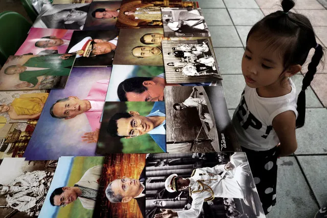 A girl looks at portraits of Thailand's late King Bhumibol Adulyadej at a shop in Bangkok, Thailand, October 17, 2016. (Photo by Athit Perawongmetha/Reuters)