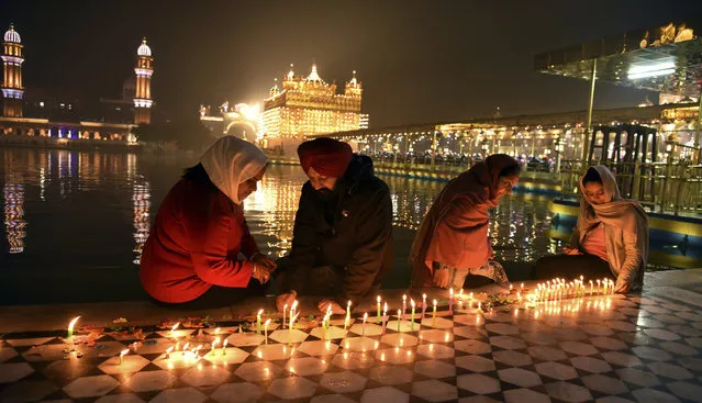 Sikh devotees light candles in the pre-dawn hours at the illuminated Golden Temple, the holiest of Sikh shrines, during the birth anniversary of Guru Nanak, the first Sikh Guru, in Amritsar, India, Monday, November 30, 2020. (Photo by Prabhjot Gill/AP Photo)