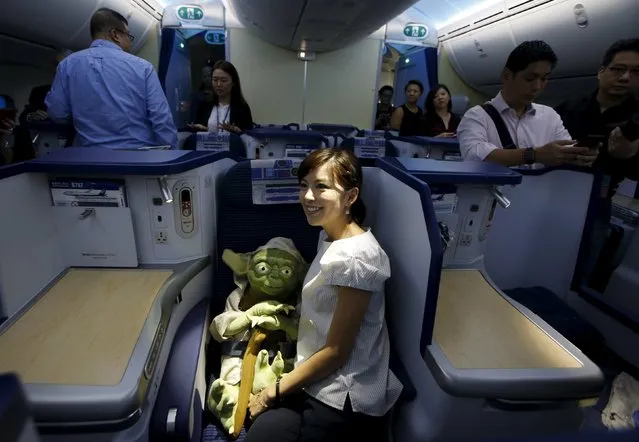 A visitor poses with a Yoda plush toy in the business class section during a tour of the "Star Wars"-themed All Nippon Airways ANA R2-D2 Boeing 787 Dreamliner aircraft at Singapore's Changi Airport November 12, 2015. (Photo by Edgar Su/Reuters)
