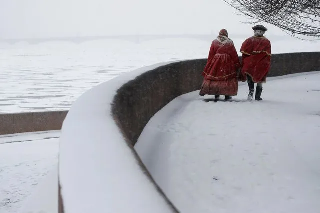 Entertainers dressed in period clothing walk along the Spit of Vasilievsky Island during snowfall in central Saint Petersburg, Russia on December 23, 2020. (Photo by Anton Vaganov/Reuters)