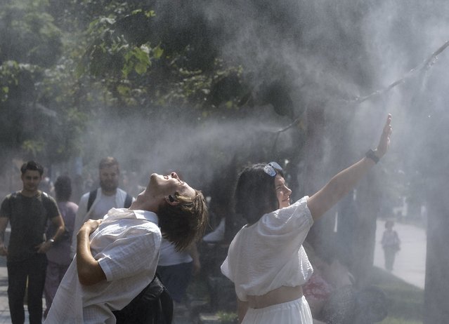 Ukrainians cool themselves with water sprayed from pipes hanging over a sidewalk at the central street of Khreshchatyk during hot weather in Kyiv, Ukraine, 17 July 2024. According to weather reports, temperatures in the Ukrainian capital reached 40 degrees Celsius during the week and are expected to remain high for several days. (Photo by Sergey Dolzhenko/EPA/EFE)