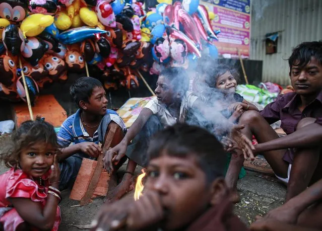 Children sit around a fire to keep themselves warm during the early morning hours along a road in Mumbai January 2, 2015. (Photo by Danish Siddiqui/Reuters)