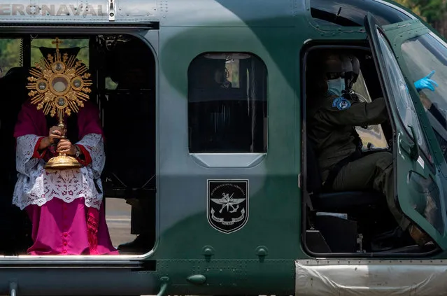 Panama's Archbishop Jose Domingo Ulloa holds the Blessed Sacrament as he sits on a helicopter at Howard Air Force Base in Panama City on April 5, 2020 before a flight over the capital and surrounding areas to “protect the country from disease” amid fears of the spread of the novel coronavirus, COVID-19. (Photo by Luis Acosta/AFP Photo)