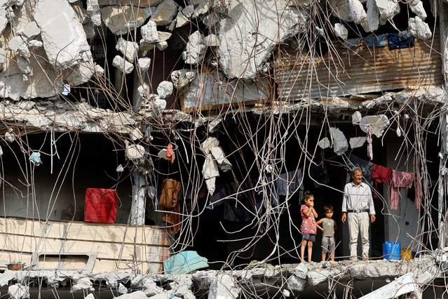 A Palestinian man and children stand at a heavily damaged building surrounded by rebar and rubble, amid a ceasefire between Israel and Hamas, in Gaza City, on November 2, 2025. (Photo by Mahmoud Issa/Reuters)