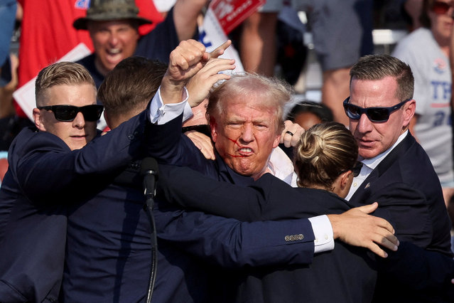 Republican presidential candidate and former President Donald Trump is assisted by the Secret Service after gunfire rang out during a campaign rally at the Butler Farm Show in Butler, Pennsylvania, on July 13, 2024. (Photo by Brendan McDermid/Reuters)
