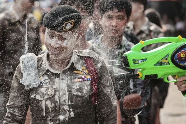 A man sprays water at a policeman to celebrate Songkran festival in Prachinburi Province, east of Bangkok. Thursday, April 13, 2023, Hordes of revelers toted colorful water guns Thursday as Thailand kicked off its exuberant three-day Songkran festival at full blast for the first time since 2019, hoping for a significant boost in tourism after the industry was devastated by coronavirus travel restrictions. (Photo by Wason Wanichakorn/AP Photo)