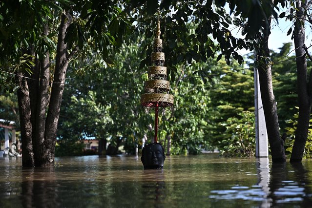 Flood waters cover a Buddha statue at Wat Taku Buddhist temple in Bang Ban district in the central Thai province of Ayutthaya on November 14, 2025. (Photo by Lillian Suwanrumpha/AFP Photo)