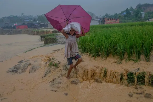 A Rohingya Muslim girl, Saira Begum carries food items distributed in aid as she walks towards her shelter in Taiy Khali refugee camp, Bangladesh, Tuesday, September 19, 2017. With a mass exodus of Rohingya Muslims sparking accusations of ethnic cleansing from the United Nations and others, Myanmar leader Aung San Suu Kyi on Tuesday said her country does not fear international scrutiny and invited diplomats to see some areas for themselves. (Photo by Dar Yasin/AP Photo)