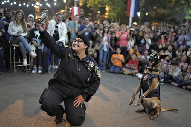 Police dog instructor Adriana Ayala poses with her dog for a selfie during an exhibition to celebrate the 212th Anniversary of Paraguay´s Independence from Spain, in Asunción, Paraguay, Sunday, May 14, 2023. (Photo by Jorge Saenz/AP Photo)
