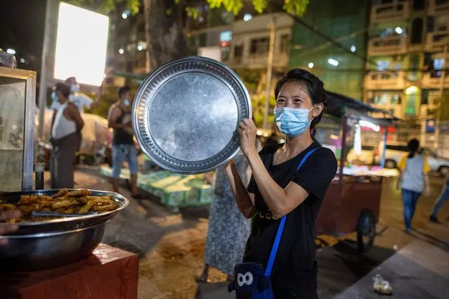 A woman hits a plate during a night protest against the military coup in Yangon, Myanmar on February 4, 2021. (Photo by Reuters/Stringer)