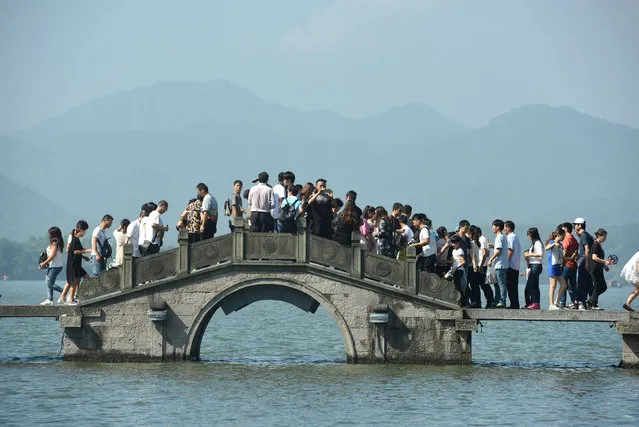 Visitors walk on a bridge on West Lake during China's golden week holiday in Hangzhou, Zhejiang Province, China, October 2, 2016. (Photo by Reuters/Stringer)