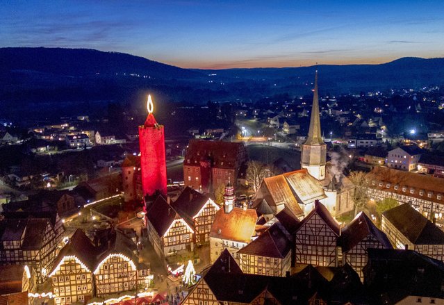 A 42-meter-high candle which is an illuminated medieval tower shines in the historic city centre of Schlitz, Germany, Saturday, November 30, 2024. (Photo by Michael Probst/AP Photo)