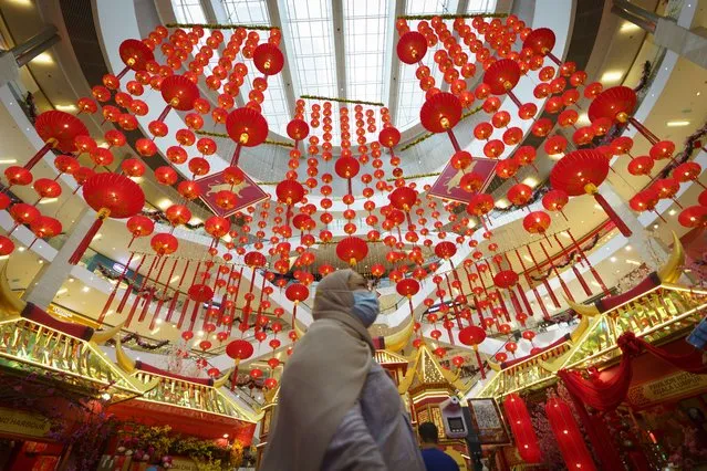A woman wears a face mask walking under Chinese Lunar New Year decoration at a shopping mall in Kuala Lumpur, Malaysia, Tuesday, February 16, 2021. The movement control order (MCO) currently enforced across the country, has been extended to March 4 in some of the states, to try to halt the spread of the coronavirus. (Photo by Vincent Thian/AP Photo)