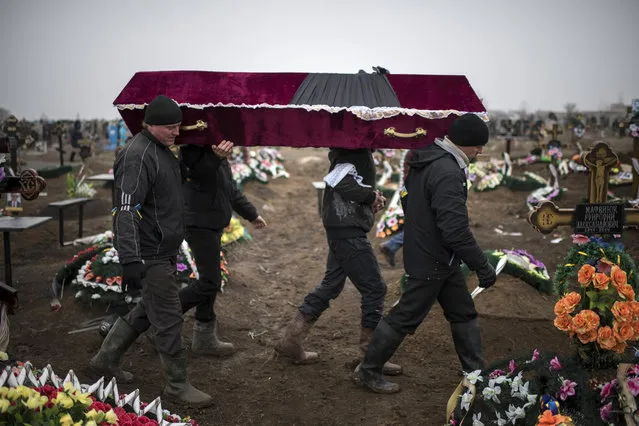 Ukrainian municipal woakers carry a coffin bearing the body of Vitaliy Sirotenko, who was killed Saturday during an attack in Mariupol, Ukraine, on  Tuesday January 27, 2015. A lull in the fighting in December had raised hopes for a peaceful settlement, but hostilities have escalated again in recent weeks as the rebels launched a series of new offensives. (Photo by Evgeniy Maloletka/AP Photo)