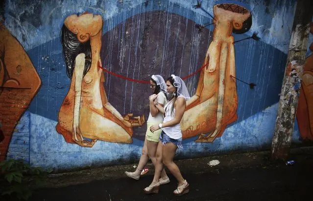 Revellers walk past a graffiti as she arrives at the annual carnival block party known as “Casas comigo” or “Marry me” at the Vila Madalena neighborhood  in Sao Paulo February 1, 2015. (Photo by Nacho Doce/Reuters)