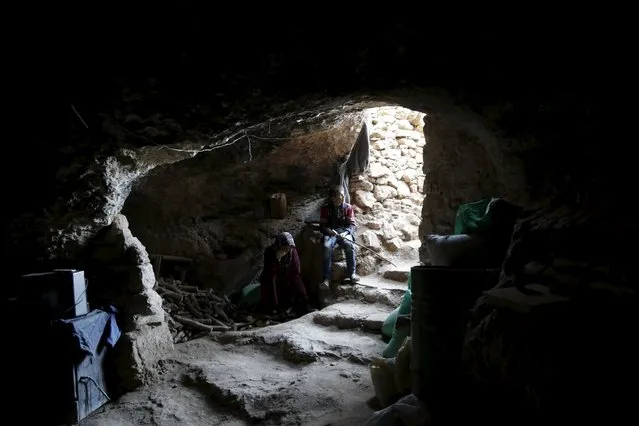 Internally displaced Syrians sit inside their makeshift shelter that is an underground cave in Om al-Seer, southern Idlib countryside, Syria December 26, 2015. (Photo by Khalil Ashawi/Reuters)
