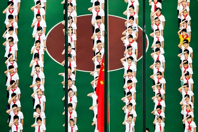 This aerial photo shows children lining up for a flag- raising ceremony on their first day back to school after the summer holidays, at the playground of a middle school in Shanghai on September 3, 2018. (Photo by Johannes Eisele/AFP Photo)