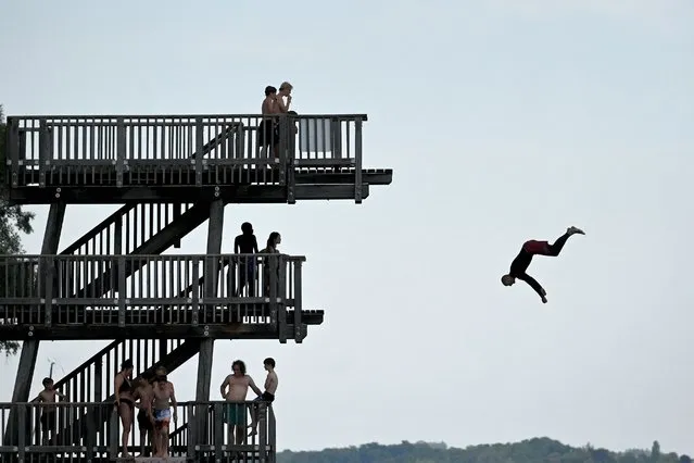 A man jumps from a diving platform into Lake Ammersee near the Bavarian village of Utting, southern Germany, during warm summer weather with temperatures around 30 degrees Celsius, on August 17, 2023. (Photo by Christof Stache/AFP Photo)