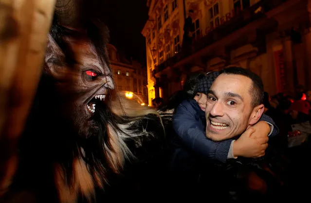 A man and his child react at reveller dressed as a devil, on the eve of Saint Nicholas Day, at the Old Town Square in Prague, Czech Republic December 5, 2016. (Photo by David W. Cerny/Reuters)