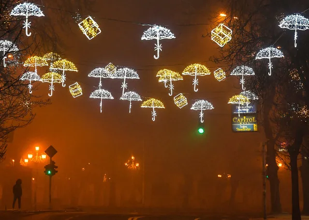 A man walks through the empty decorated street during heavy fog and air pollution that cover Skopje valley, in Skopje, Republic of North Macedonia, 24 December 2020. Heating season, fog, smog and pollution put the capital Skopje on the list of the most polluted cities in the world. Poor air quality, combined with the big number of newly infected people with COVID-19 disease complicates the health situation in the country. (Photo by Georgi Licovski/EPA/EFE)