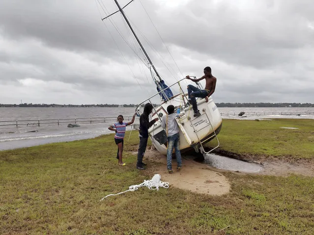 Youth look over a sailboat that washed ashore from the Neuse River, near East Front Street in New Bern, N.C., September 15, 2018. The boat was carried by storm surge and flooding from Hurricane Florence. (Photo by Gray Whitley/Sun Journal via AP Photo)