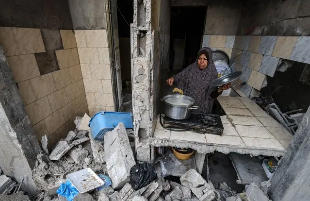 A Palestinian woman who has returned to her neighbourhood, cooks a meal in what remains of her home, hit by Israeli bombardment in Gaza City, after a ceasefire brokered by Egypt between Israel and Hamas, on May 21, 2021. A ceasefire between Israel and Hamas, the Islamist movement which controls the Gaza Strip, appeared to hold today after 11 days of deadly fighting that pounded the Palestinian enclave and forced countless Israelis to seek shelter from rockets. (Photo by Mohammed Abed/AFP Photo)