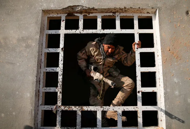 A member of the Iraqi Army gets over a window during clashes with Islamic State militants at the south of Mosul, Iraq December 12, 2016. (Photo by Ammar Awad/Reuters)