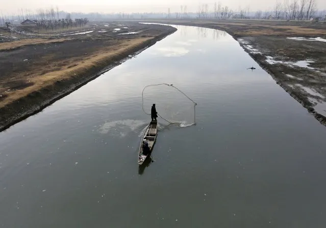 A fisherman casts his net in the waters of a flood channel on the outskirts of Srinagar January 19, 2016. (Photo by Danish Ismail/Reuters)