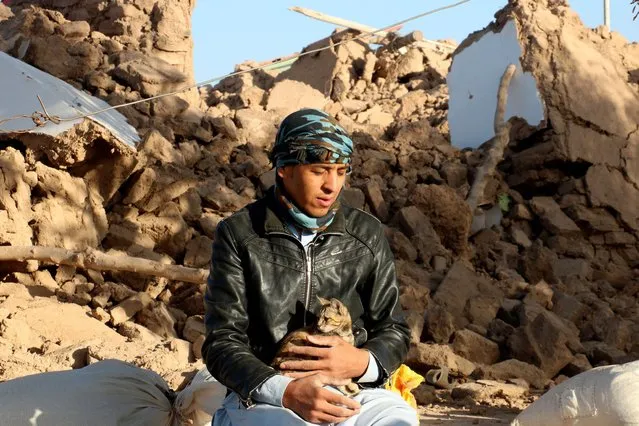 An Afghan boy hold his cat, as he sits in a courtyard of his destroyed home after an earthquake in Zenda Jan district in Herat province, of western Afghanistan, Sunday, October 8, 2023. Powerful earthquakes killed at least 2,000 people in western Afghanistan, a Taliban government spokesman said Sunday. It's one of the deadliest earthquakes to strike the country in two decades. (Photo by Omid Haqjoo/AP Photo)