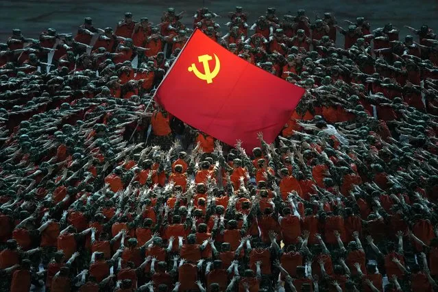 Performers dressed as rescue workers gather around the Communist Party flag during a gala show ahead of the 100th anniversary of the founding of the Chinese Communist Party in Beijing on Monday, June 28, 2021. China is marking the centenary of its ruling Communist Party this week by heralding what it says is its growing influence abroad, along with success in battling corruption at home. (Photo by Ng Han Guan/AP Photo)