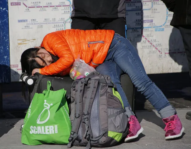 A woman sleeps on her luggage in front of the Beijing Railway Station during the travel rush ahead of the upcoming Spring Festival in Beijing, China, February 2, 2016. (Photo by Kim Kyung-Hoon/Reuters)