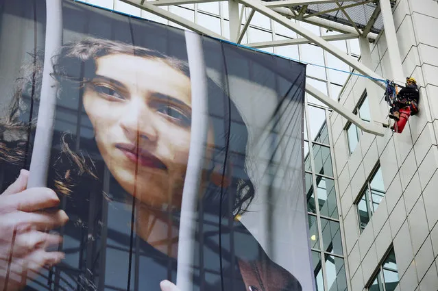 Members of Greenpeace hang a large poster of Dutch activist Faiza Oulahsen on the office building of Shell during a protest calling for the release of the “Arctic 30” in Rotterdam on November 21, 2013. Russia arrested Oulahsen along with 29 other crew members of the Arctic Sunrise after activists in September scaled an oil rig in the Barents Sea owned by energy giant Gazprom. (Photo by Martijn Beekman/AFP Photo/ANP)