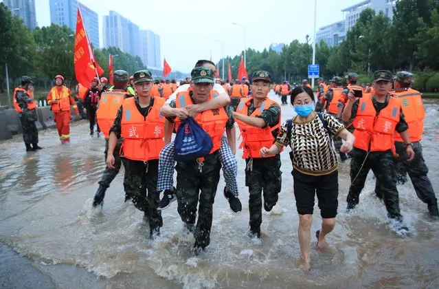 Chinese military personnel evacuate residents from a hospital where about 3,000 people were trapped by the flood in Zhengzhou in central China's Henan province Thursday, July 22, 2021. Residents of the storm-ravaged central Chinese city of Zhengzhou on Thursday were shoveling mud from their homes and hauling away wrecked cars and piles of destroyed belongings following floods that killed at least 33 people in the city and surrounding areas. (Photo by Chinatopix via AP Photo)