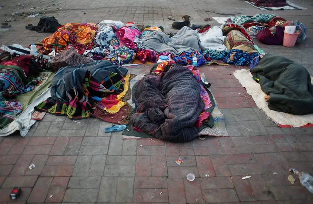 People wrapped in blankets sleep on a road divider on a cold winter morning in New Delhi, India, December 18, 2018. (Photo by Adnan Abidi/Reuters)