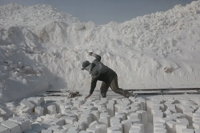 In this Wednesday, March 18, 2015 photo, a quarry workers wearing a face mask to protect from dust tries to stay balanced while arranging cut stones at a quarry in the desert of Minya, southern Egypt. (Photo by Mosa'ab Elshamy/AP Photo)