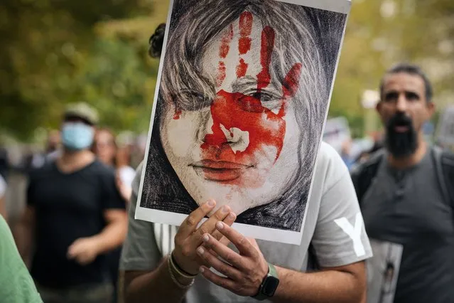 A man holds a placard during a protest against the death of Iranian Mahsa Amini, in Bucharest, Romania, Saturday, October 1, 2022. Amini, a 22-year-old woman who died in Iran while in police custody, was arrested by Iran's morality police for allegedly violating its strictly-enforced dress code. (Photo by Vadim Ghirda/AP Photo)