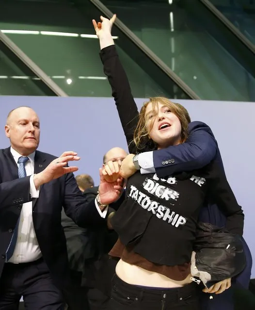 Security officers detain a protester who jumped on the table in front of the European Central Bank President Mario Draghi during a news conference in Frankfurt, April 15, 2015. (Photo by Kai Pfaffenbach/Reuters)