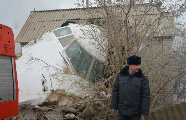A police officer stands by the wreckage of a Turkish cargo plane at the crash site in the village of Dacha-Suu outside Bishkek on January 16, 2017. A Turkish cargo plane crashed into a village near Kyrgyzstan's main airport Monday, killing at least 37 people and destroying houses after attempting to land in thick fog, authorities said. (Photo by Vyacheslav Oseledko/AFP Photo)