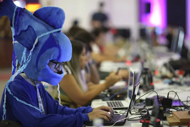 In this February 12, 2019 photo, participants play games during the Campus Party technology festival, one in costume, in Sao Paulo, Brazil. Campus Party is an annual, week-long, 24-hour technology festival that gathers developers, gamers and computer enthusiasts. (Photo by Andre Penner/AP Photo)