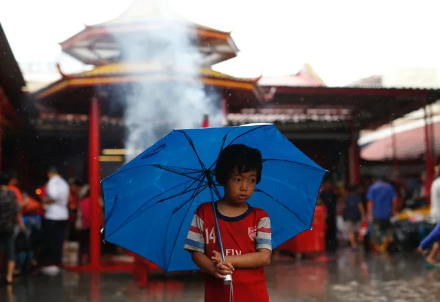 A boy waits in the rain to rent out his umbrella as people celebrate the Lunar New Year at Dharma Bhakti temple in Jakarta, Indonesia January 28, 2017. (Photo by Darren Whiteside/Reuters)