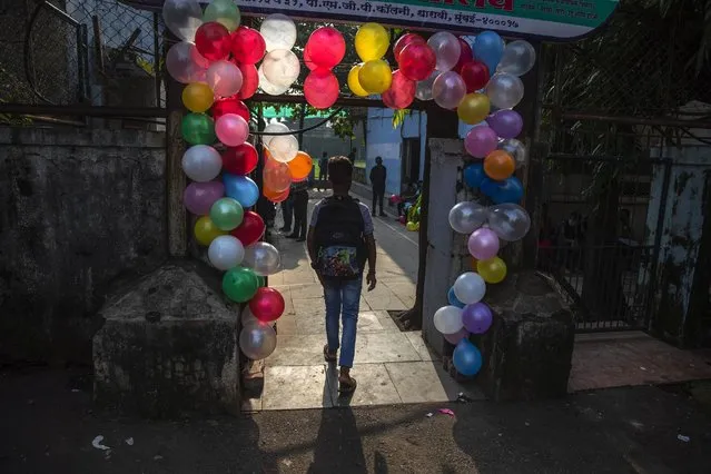 A student walks in through an entrance decorated with balloons during the partial reopening of a school that remained closed due to the coronavirus pandemic at Dharavi, one of Asia's largest slums, in Mumbai, India, Monday, October 4, 2021. (Photo by Rafiq Maqbool/AP Photo)