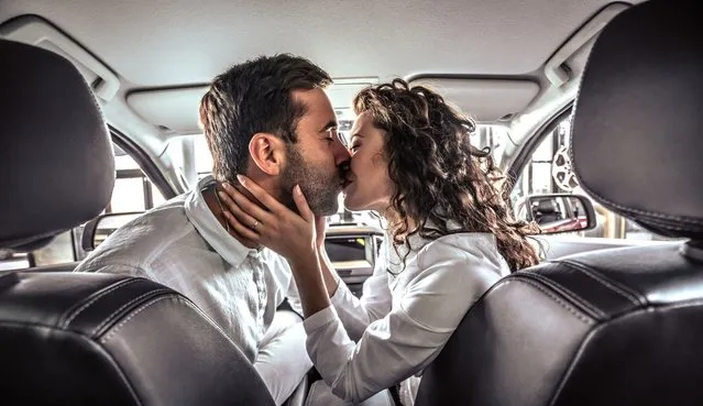 Happy beautiful couple in love kissing in a new car in car dealership. (Photo by Harbucks/Getty Images)