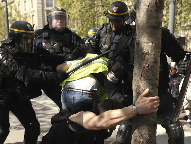 A police officer scuffle with protestors during a yellow vest demonstration in Paris, Saturday, April 20, 2019. French yellow vest protesters are marching anew to remind the government that rebuilding the fire-ravaged Notre Dame Cathedral isn't the only problem the nation needs to solve. (Photo by Francisco Seco/AP Photo)