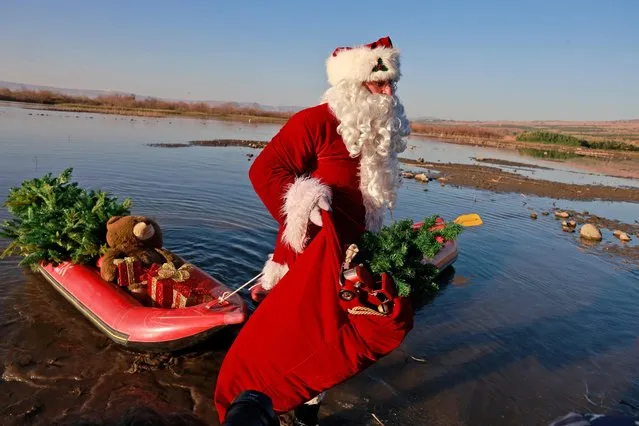 Issa Kassissieh, better known as the Santa Claus of Jerusalem, gets off a kayak on the shore of the Sea of Galilee at the location believed to be that of a biblical village that was home to Saint Peter, on November 10, 2021. (Photo by Menahem Kahana/AFP Photo)
