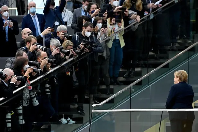 Outgoing German Chancellor Angela Merkel is in the focus of photographers as she stands on the tribune prior to a session at the Bundestag (lower house of parliament) in Berlin on December 8, 2021 to elect the country's next Chancellor. Members of the parliament are to elected Olaf Scholz, bringing the curtain down on Angela Merkel's 16-year reign, ushering in a new political era with the centre-left in charge. Together with the Greens and the liberal Free Democrats, Scholz's SPD managed in a far shorter time than expected to forge a coalition that aspires to make Germany greener and fairer. (Photo by Ina Fassbender/AFP Photo)