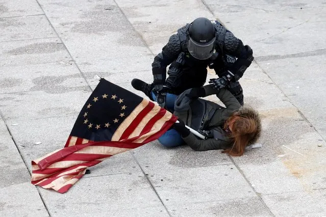 A police officer detains a pro-Trump protester as mobs storm the U.S. Capitol, during a rally to contest the certification of the 2020 U.S. presidential election results by the U.S. Congress, at the U.S. Capitol Building in Washington, U.S, January 6, 2021. (Photo by Shannon Stapleton/Reuters)