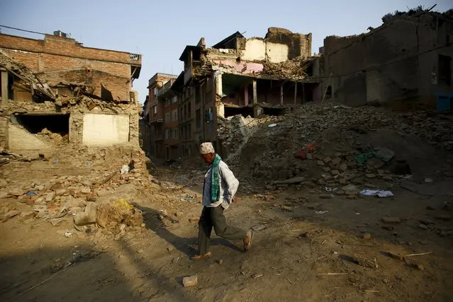 A man walks along a street near collapsed houses, a month after the April 25 earthquake in Kathmandu, Nepal May 25, 2015. (Photo by Navesh Chitrakar/Reuters)